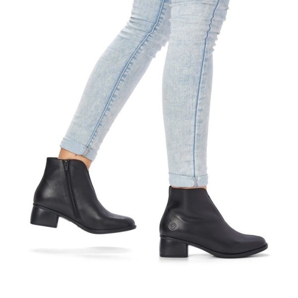 Legs in jeans wearing black leather ankle boot with block heel.