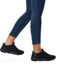 Women in jeans wearing black mesh slip on sneaker.