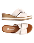 Top and side view of white leather slide wedge sandal with bow. Remonte logo on brown insole.