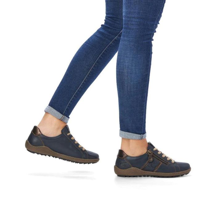 Legs in jeans wearing navy lace-up sneakers.