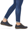 Legs in jeans wearing navy lace-up sneakers.