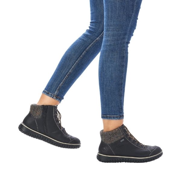 Model wearing black Rieker Z4243 waterproof ankle boots with jeans, showcasing flexible sole and stylish winter-ready design.