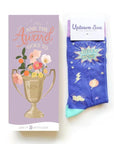 Mothers day card and socks. Card has floral filled trophy and reads "And the award goes to Mom" Purple socks have lightning bolts and reads "Super Mom"