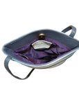Open view of Anuschka's blue leather handbag showing purple lining.