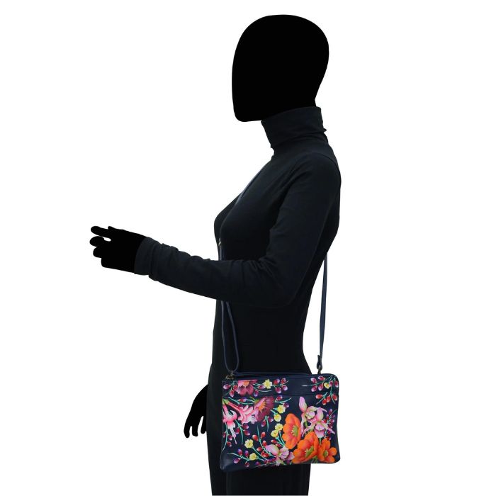 Black human silhouette showcasing the navy leather crossbody bag with vibrant floral hand painted pattern.