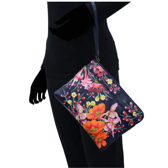 Black human silhouette showcasing the navy leather wristlet bag with vibrant floral hand painted pattern.