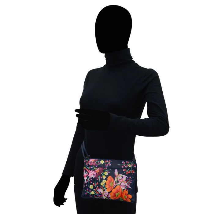 Black human silhouette showcasing the navy leather bag with vibrant hand painted floral pattern.