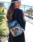 Women in black wearing a black backpack with vibrant leopard and floral print.