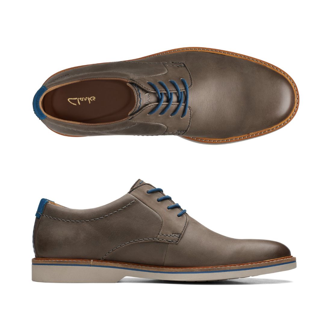 Top and side view of taupe leather dress shoe with blue laces and off white outsole. Clarks logo on heel of insole.